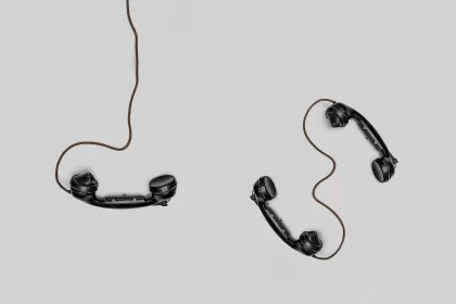 Two old-fashioned black telephone handsets with cords placed on a light gray background, symbolizing broken or unclear communication, and representing communication between IT and business