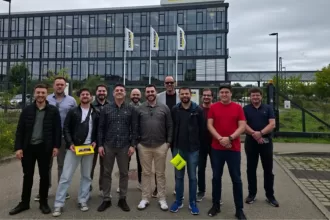 TestBooster team standing in front of the Kärcher headquarters building in Germany, posing for a photo with the company logo and flags visible in the background.