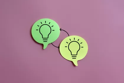 Two green speech bubbles with lightbulb icons connected by arrows, symbolizing idea sharing or knowledge transfer, on a pink background, representing types of software testing