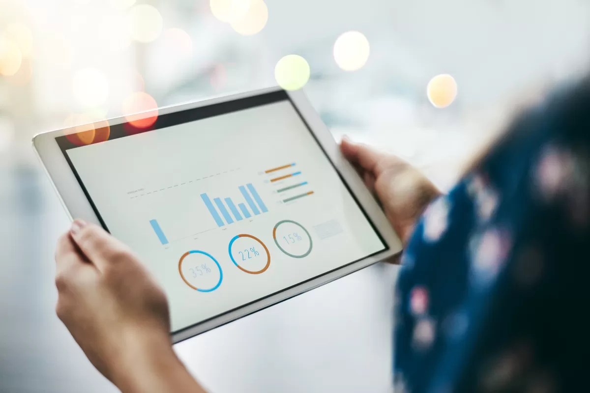 Pessoa segurando tablet com painel de analytics e gráficos de desempenho, representando como testar sistemas ERP