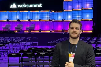Gustavo Liu, COO do TestBooster.ai, no palco principal do Web Summit Lisboa 2025 com telão e iluminação roxa ao fundo