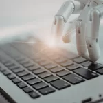 Mão robótica digitando em um teclado de computador