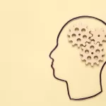 Ilustração minimalista em fundo bege com o contorno de um perfil humano e três engrenagens de madeira posicionadas onde seria o cérebro, simbolizando lógica e processos.