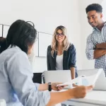 Time de desenvolvedores em reunião de trabalho com laptops, representando colaboração e comunicação entre diferentes níveis de QA