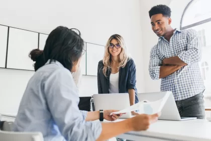 Time de desenvolvedores em reunião de trabalho com laptops, representando colaboração e comunicação entre diferentes níveis de QA